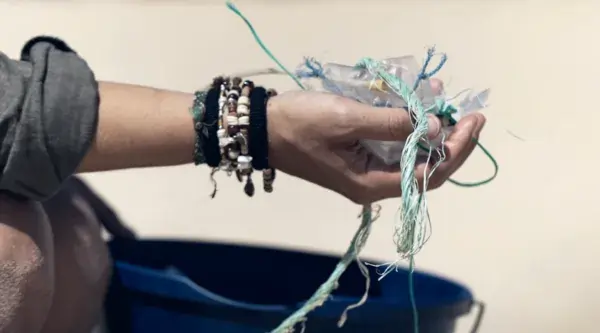 Bénévole ramassant des déchet plastique sur la page